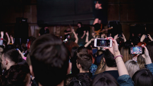 人们在音乐会期间用触摸智能手机拍照