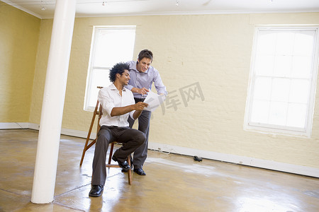 两个带梯子的男人在空荡荡的空间里看着纸