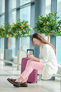 智能巡检摄影照片_国际机场的年轻女子带着行李和智能手机等待她的航班