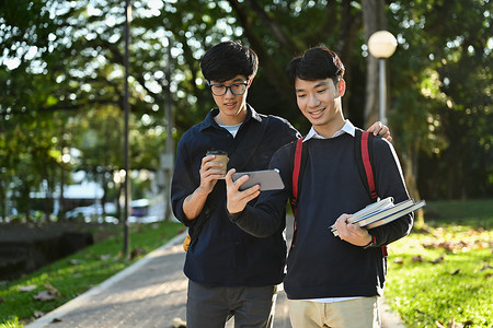 两名亚洲学生下课后在大学校园里散步时互相交谈