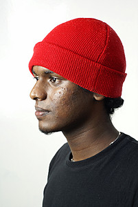白色背景上戴着红色便帽的印度男子侧面肖像