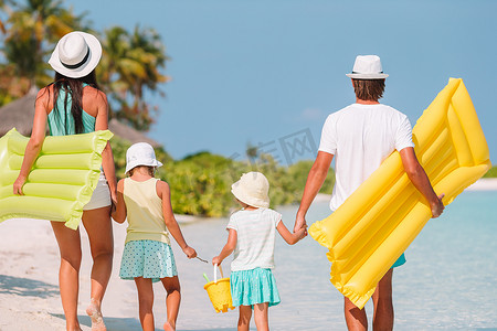 有两个孩子的家庭在热带海滩上跑步