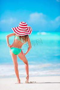 大帽子的可爱的小女孩在白色沙子加勒比海滩