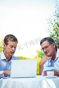 两位商人在一家餐厅使用笔记本电脑开会