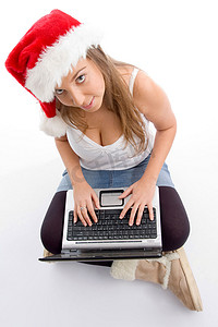 坐着的女性戴着圣诞帽拿着笔记本电脑