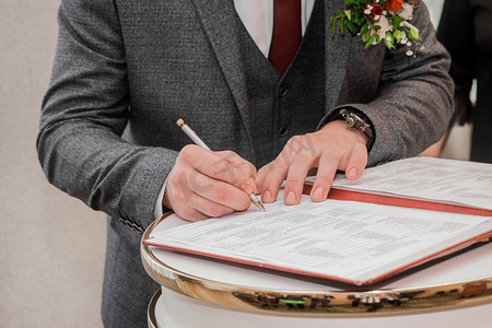 新郎的手在确认婚姻特写镜头的文件中用笔签名