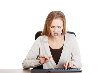 美丽的休闲女人愤怒地在键盘上写字。