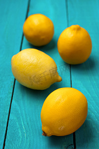 黄色青色摄影照片_在明亮的青色背景上的柠檬