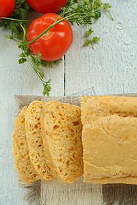 芝士奶酪面包摄影照片_桌子上是切片奶酪面包西红柿罗勒的家