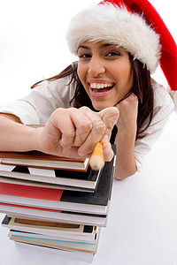 教室节日摄影照片_戴着圣诞帽、拿着一摞书的快乐学生