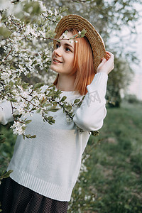樱花中戴草帽的女人画像。