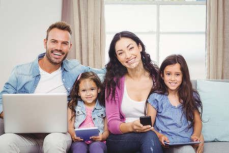坐在沙发上使用现代技术的幸福家庭