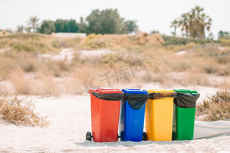 垃圾桶分类垃圾桶摄影照片_海滩上垃圾分类的四个塑料容器。