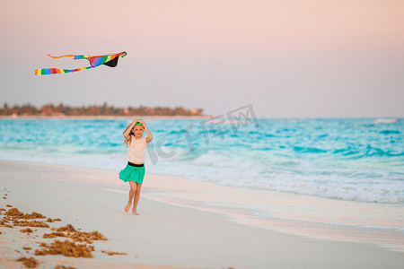 游戏娱乐摄影照片_在热带海滩上放风筝的小奔跑女孩。