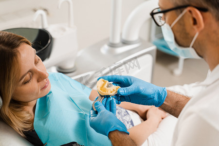 牙医在种植牙前展示患者女性的牙齿模型。
