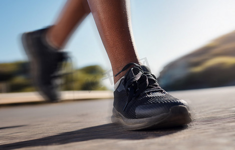 一个女人在自然界的道路上快速奔跑的健身鞋、跑步和训练。