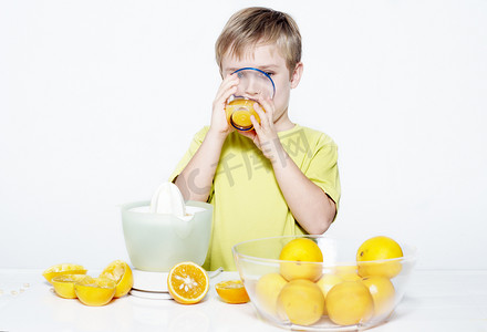 儿童浅色背景摄影照片_浅色背景下喝橙汁的男孩