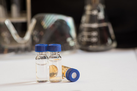 实物水生物摄影照片_实验室玻璃器皿前的蓝色瓶盖小瓶