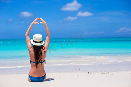 有魅力的年轻女人用手在沙滩上做一颗心