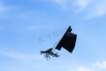 一个毕业帽或灰浆板被抛向空中，天空背景