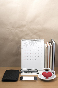 叠杯子摄影照片_桌面：带电话的咖啡、一叠书、钱包、心、眼镜