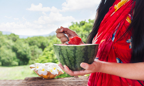 西瓜地摄影照片_专注于勺子上的西瓜和拿着西瓜的女性手