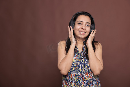 戴着无线耳机享受音乐的微笑印度女性