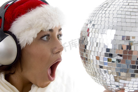 圣诞帽服装摄影照片_惊讶的女人看着迪斯科舞会，戴着圣诞帽