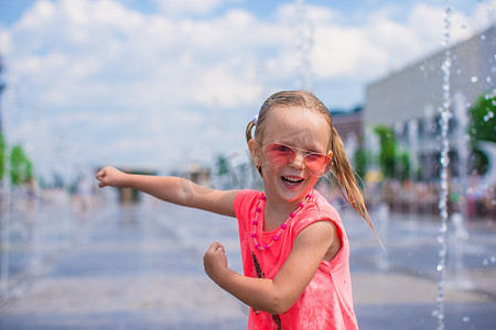 清爽一夏天摄影照片_阳光明媚的炎热日子里，快乐的小女孩在街头喷泉里玩得开心