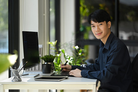 在现代公司办公室的台式计算机上从事软件开发的帅哥程序员画像