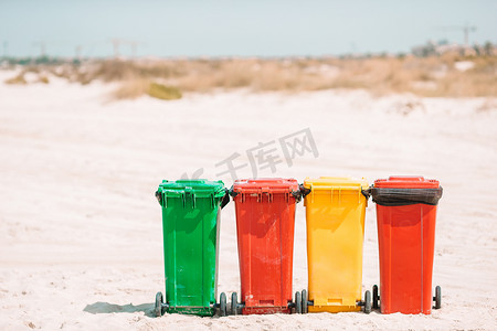 垃圾桶分类垃圾桶摄影照片_海滩上垃圾分类的四个塑料容器。