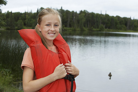 站在湖边穿着救生衣的年轻女孩的画像