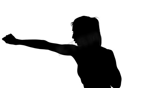 在白色背景上，一个影子，一个女性人物的黑色轮廓做拳击动作，与影子的战斗，跆拳道，模仿打击，战斗技巧，
