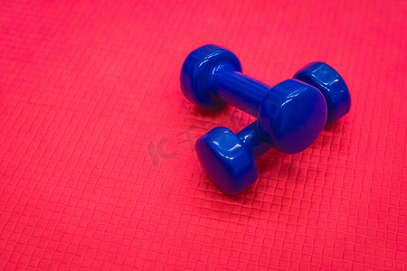 在健身房的红色地板背景的蓝色哑铃健身重量设备
