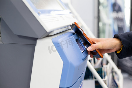 使用智能手机通过 NFC 在售票机上扫描的女性