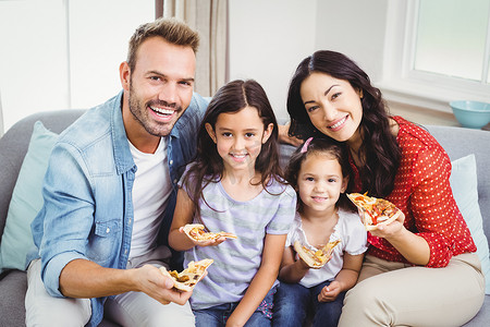 幸福的家庭坐在沙发上吃披萨