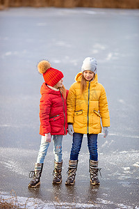 可爱的女孩在冬季雪天在户外溜冰场滑冰