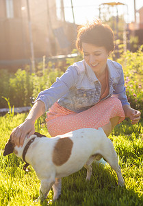 年轻女子在后院的草地上和她的狗玩耍。