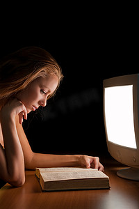 女孩在工作电脑的灯光下读书
