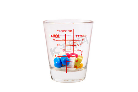 在量杯的许多五颜六色的药片在白色背景的玻璃。