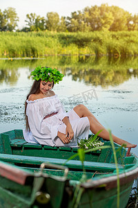 这位仙女留着长长的黑发，穿着一件白色的复古连衣裙，坐在河中央的一条船上。