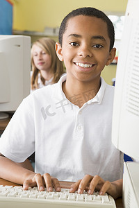 学生在计算机终端打字，背景是学生（选择性焦点）