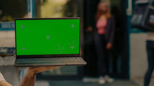 男子手持笔记本电脑，显示屏上有绿屏
