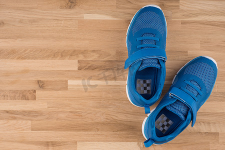 木制背景的蓝色运动鞋