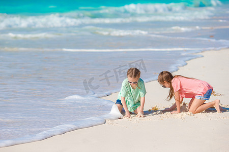 可爱的小孩一起在白色沙滩上的沙滩上画画玩得开心