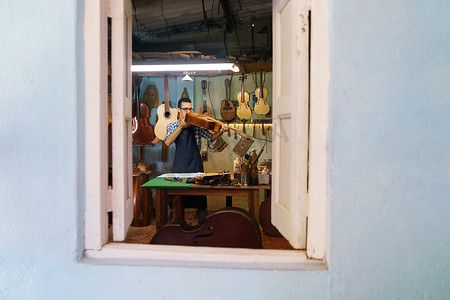 古典乐器琵琶摄影照片_琵琶制造商在乐器工作室检查古典吉他