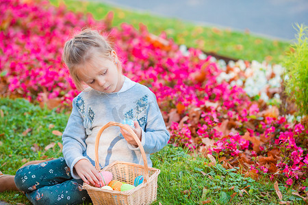 复活节坐在草地上，带着复活节彩蛋的小孩