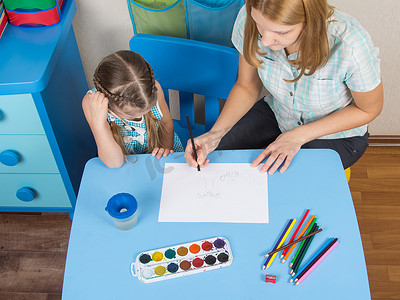 幼儿园教学摄影照片_桌上的导师和五岁女孩在幼儿园画了一幅画