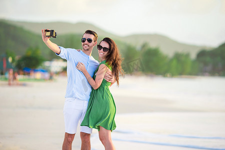 蜜月假期在白色沙滩上拍照的幸福情侣