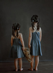女孩长图摄影照片_两个女孩背对着手，手里拿着一只泰迪熊。